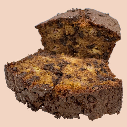 Chocolate banana bread with a slice cut, on a white plate against a light blue background