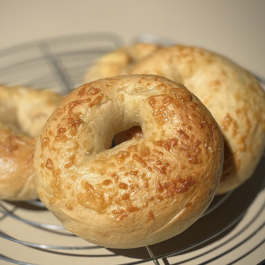Three golden-brown baked Queijo bagels resting on a wire cooling rack at cafeAtaraxia in Parede, Portugal.  The best bagels in Portugal.
